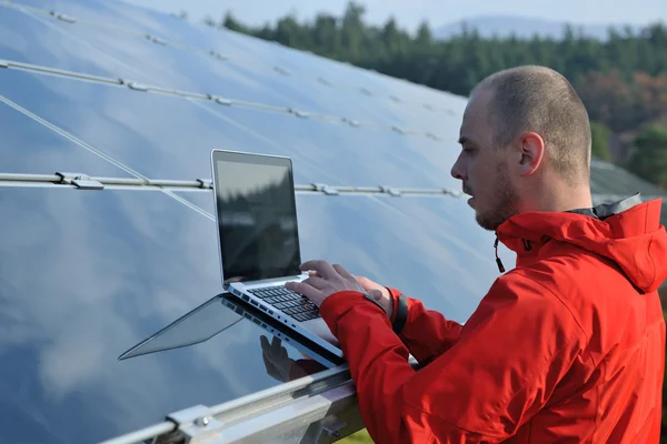 Ingegnere che utilizza il computer portatile al campo dell'impianto dei pannelli solari — Foto Stock