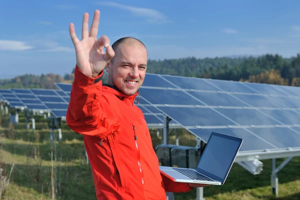 Ingegnere che utilizza il computer portatile al campo dell'impianto dei pannelli solari — Foto Stock