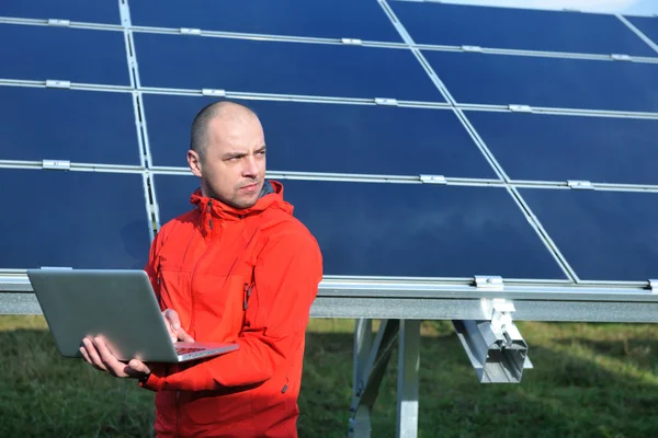 Ingénieur utilisant un ordinateur portable au champ d'usine de panneaux solaires Images De Stock Libres De Droits