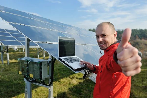 Ingénieur utilisant un ordinateur portable au champ d'usine de panneaux solaires Photo De Stock