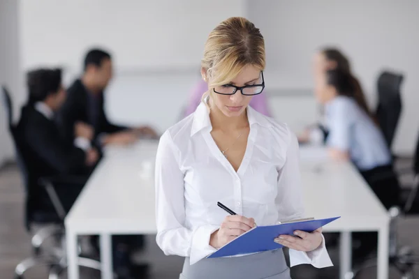 Business woman standing with her staff in background — Stock Photo, Image