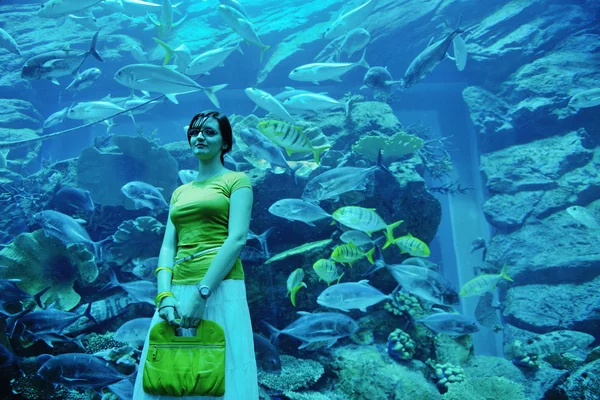 Молодая женщина с большим аквариумом в backgrond — стоковое фото