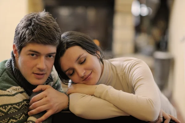 Молода романтична пара сидить на дивані перед каміном на h — стокове фото