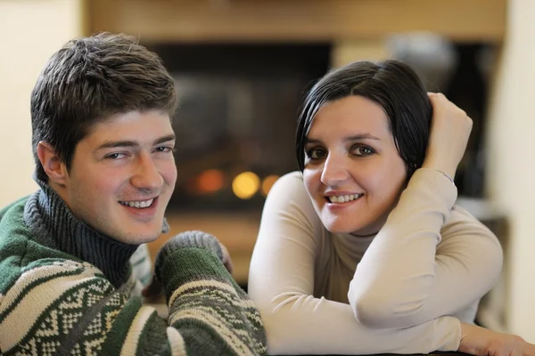 Молодая романтическая пара сидит на диване перед камином в час — стоковое фото