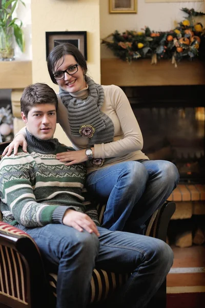 Mladý romantický pár sedí na pohovce u krbu v h — Stock fotografie