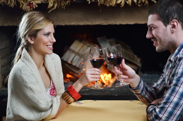 stock image Young romantic couple sitting on sofa in front of fireplace at h