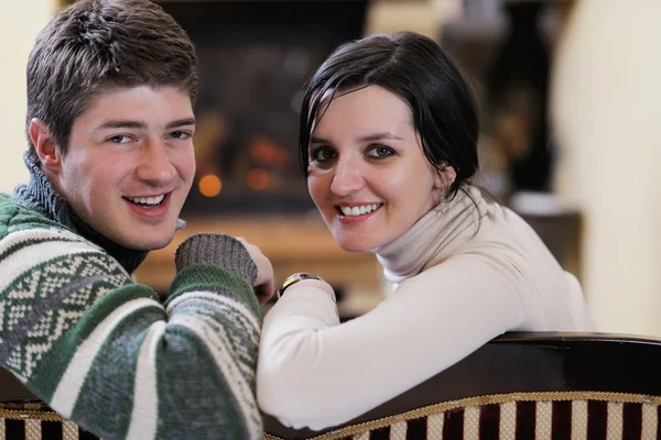 Junges romantisches Paar sitzt auf Sofa vor Kamin bei h — Stockfoto