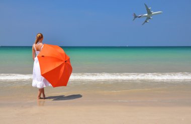 kumlu sahilde turuncu bir şemsiye ile kız