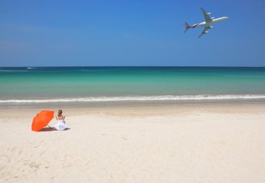 kumlu sahilde turuncu bir şemsiye ile kız