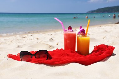 Pair of fruit shakes, red shawl and sunglasses on the beach of P clipart