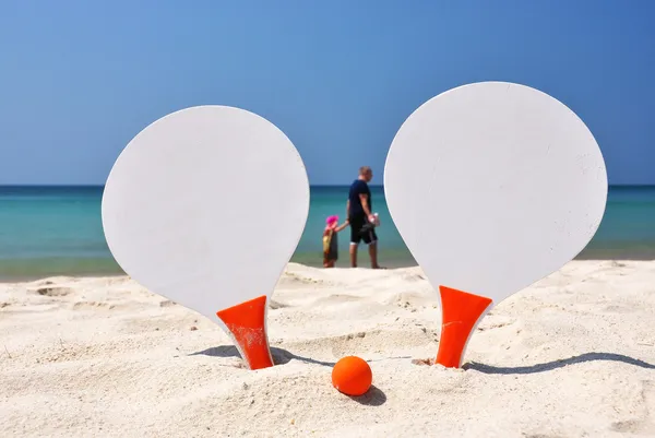 Dos raquetas y una pelota en la playa de arena — Foto de Stock