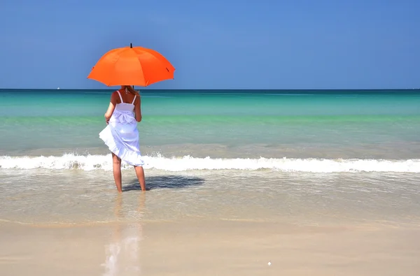 Ragazza con un ombrellone arancione sulla spiaggia di sabbia — Foto Stock