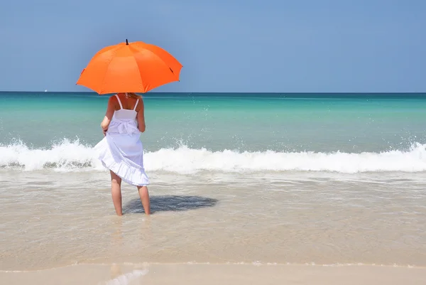 Meisje met een oranje paraplu op het zandstrand — Stockfoto