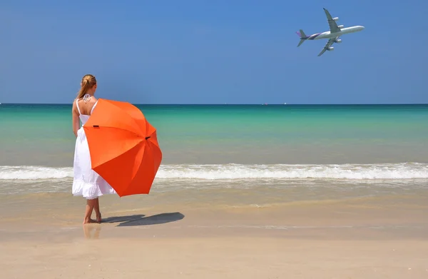 Meisje met een oranje paraplu op het zandstrand — Stockfoto