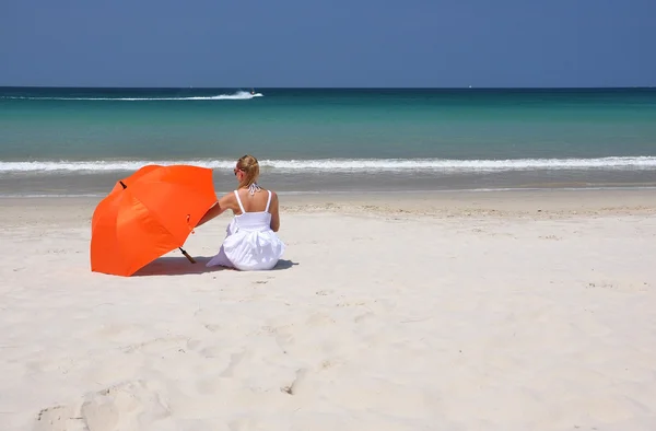 Kumlu sahilde turuncu bir şemsiye ile kız — Stok fotoğraf