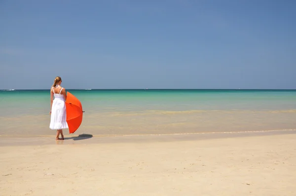 Chica con un paraguas naranja en la playa de arena —  Fotos de Stock