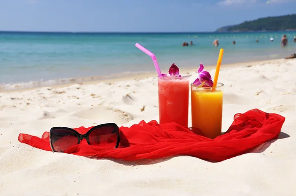 Par de batidos de frutas, chal rojo y gafas de sol en la playa de P — Foto de Stock