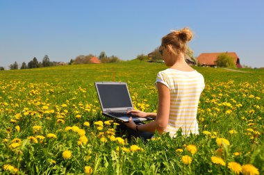 Bahar çayır üstünde a laptop ile kız