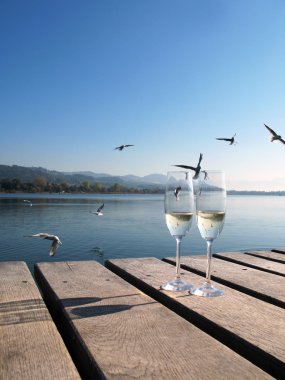 Two champagne glasses against a lake