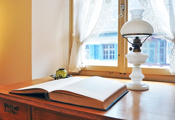 Vieja lámpara de petróleo y un libro contra ventana —  Fotos de Stock