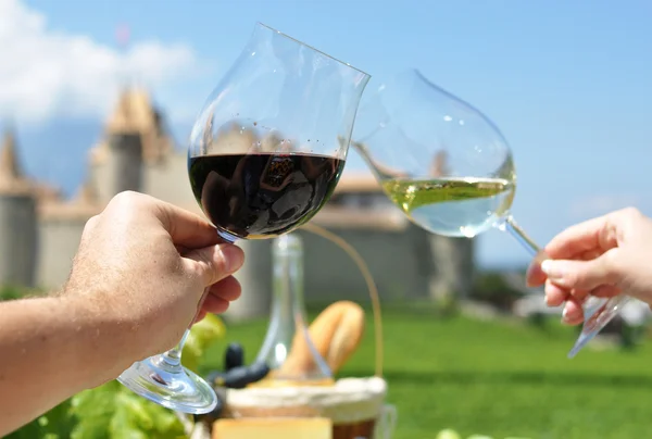 Two hands holding wineglasses against Chateau d'Aigle, Switzerla — Stock Photo, Image