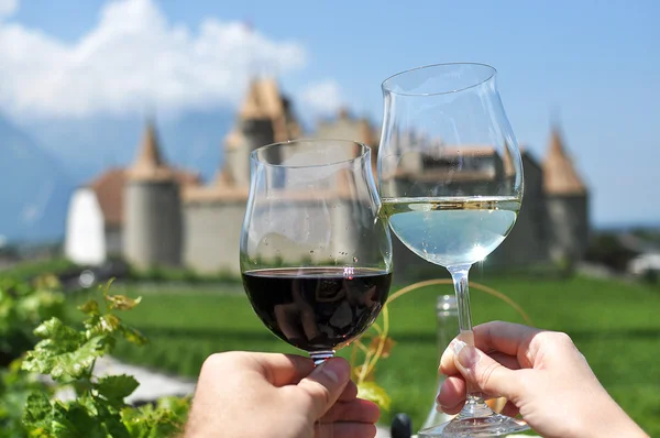 Två händer hålla vinglas mot chateau d'aigle, switzerla — Stockfoto