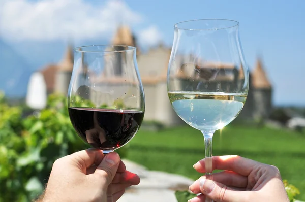 Two hands holding wineglasses against Chateau d'Aigle, Switzerla — Stock Photo, Image
