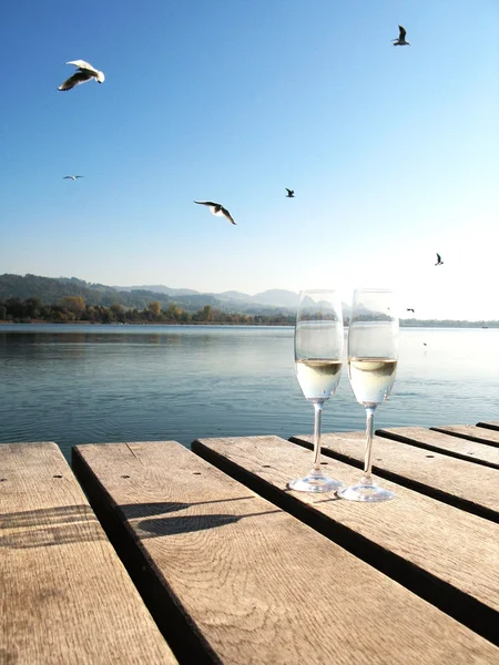 Två champagne glas mot en sjö — Stock fotografie