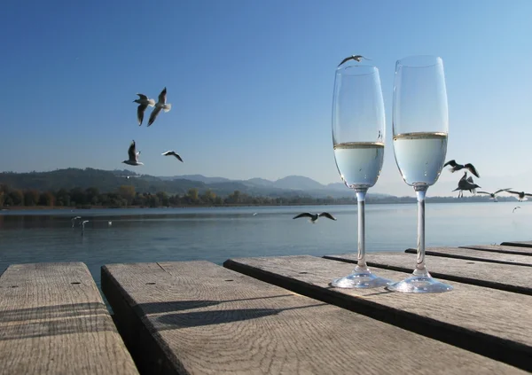 Due bicchieri di champagne contro un lago — Foto Stock