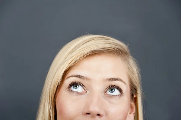 Mujer joven mira hacia arriba sobre fondo azul —  Fotos de Stock