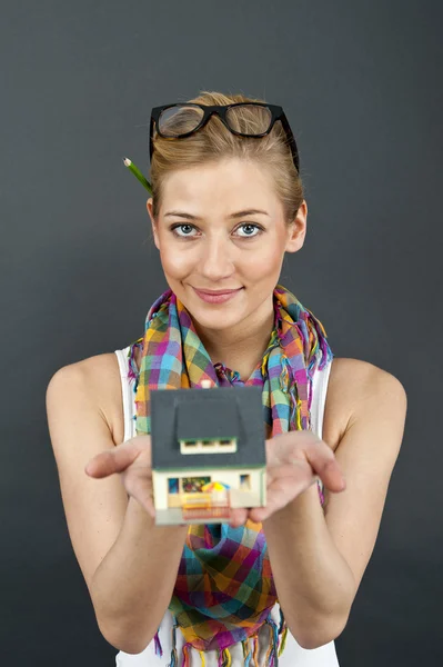 Mulher com casa em miniatura no fundo preto — Fotografia de Stock