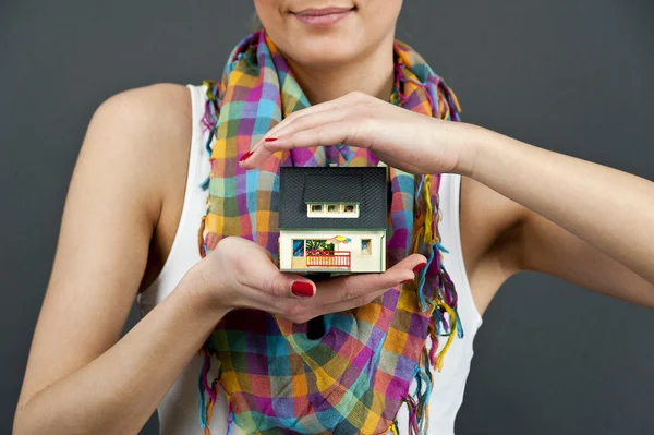 Женщина с миниатюрным домом на черном фоне — стоковое фото