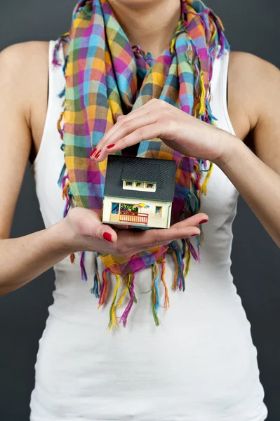 Женщина с миниатюрным домом на черном фоне — стоковое фото