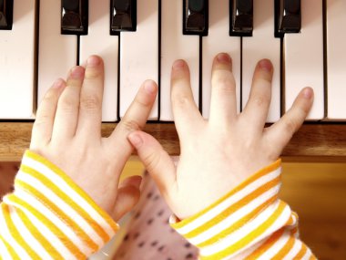 Close up of child's hands playing the piano clipart