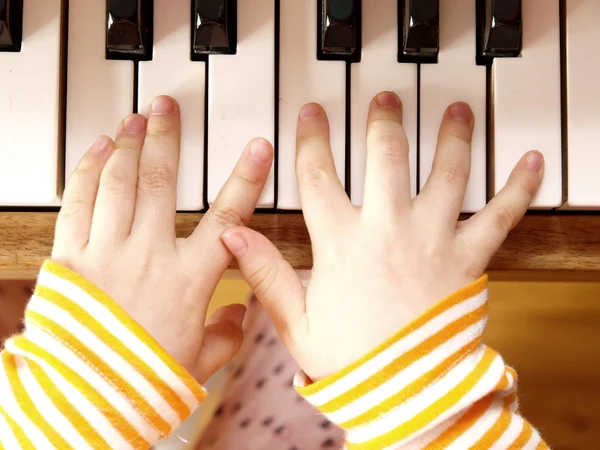 Fechar as mãos da criança tocando piano — Fotografia de Stock