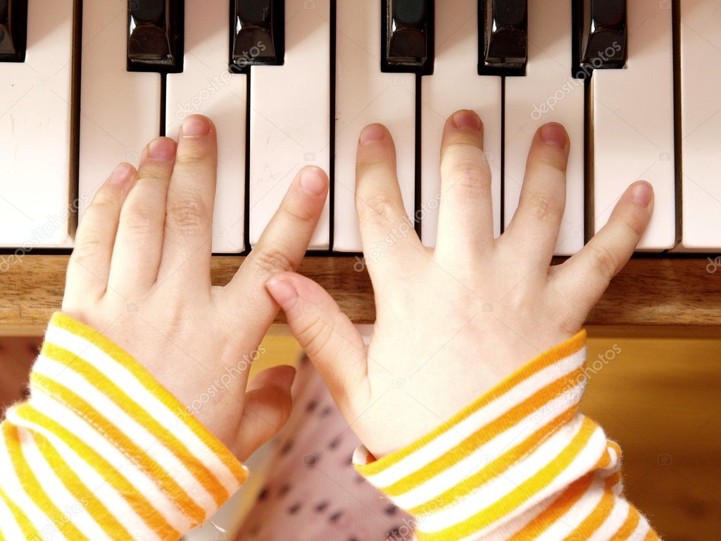 Close up of child's hands playing the piano