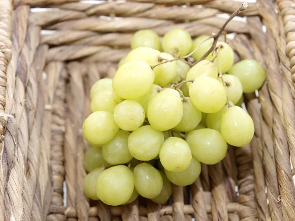 Ramo de uvas blancas maduras en una canasta de mimbre — Foto de Stock