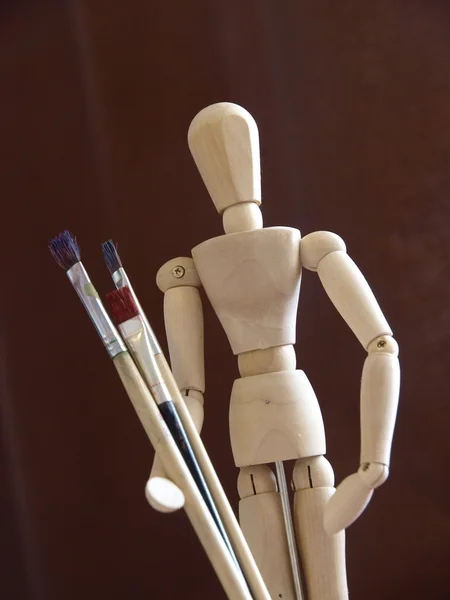 Artist's wooden mannequin with brushes — Stock Photo, Image