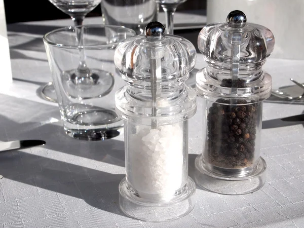 Salz und Pfeffer in Löffeln und Shakern, Lorbeerblätter auf rustikalem Holztisch — Stockfoto