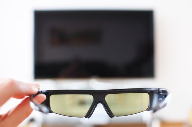 3d-glasses in the hand against TV-set clipart