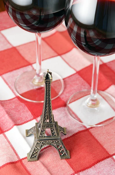 Little Eiffel tower and a pair of wineglasses on the table — Stock Photo, Image