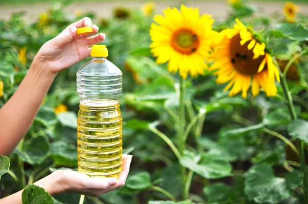 Sebotol minyak bunga matahari melawan bunga matahari — Stok Foto