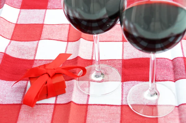 Gift box and a pair of wineglasses on the table — Stock Photo, Image