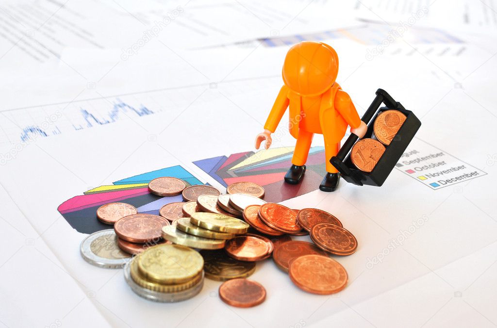 A little worker at a pile of coins against financial reports