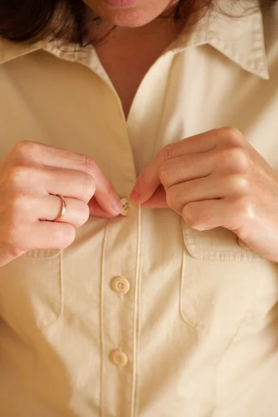 Mulher abotoando sua camisa bege — Fotografia de Stock