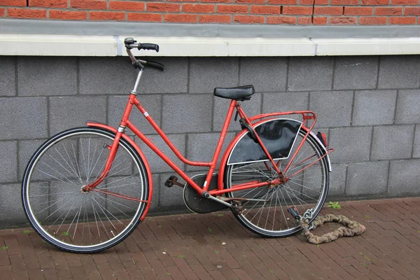Oude rode fiets tegen muur — Stockfoto