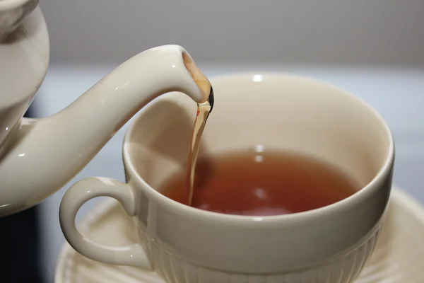 Gieten van thee in een klassieke witte theekopje — Stockfoto