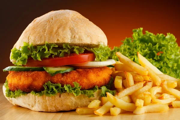 Big hamburger, French fries and vegetables — Stock Photo, Image