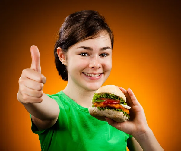 Lány eszik Nagy hamburger találat az Ok jele — Stock Fotó