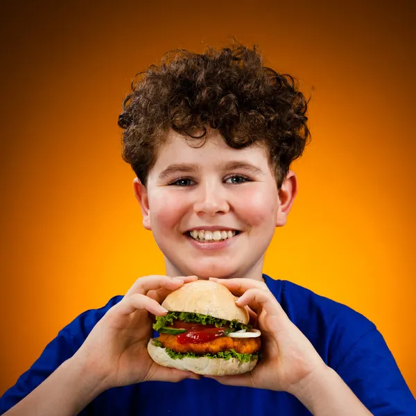 Garçon manger grand hamburger — Photo